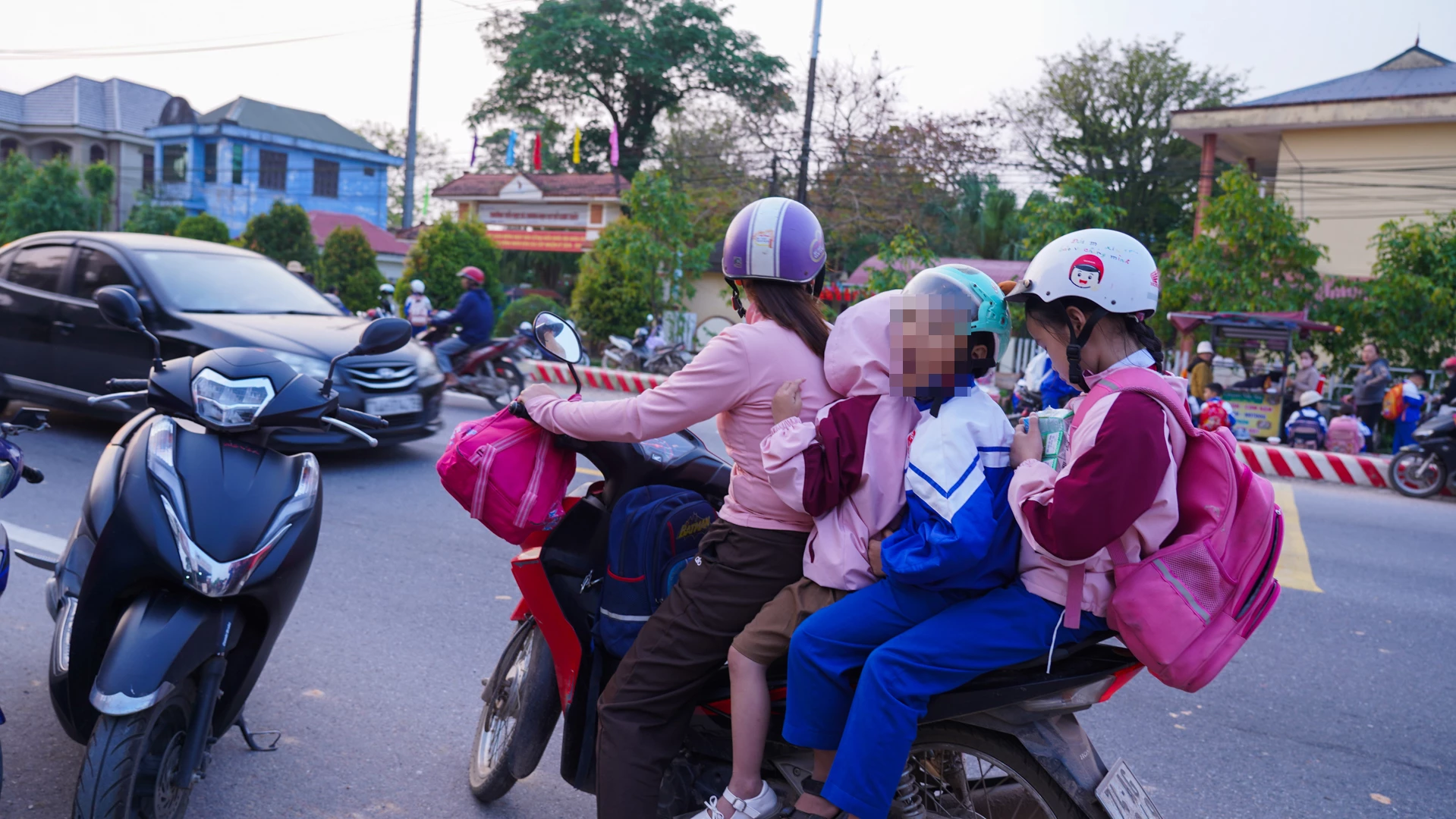 Một phụ huynh chở 3 học sinh đến trường vào sáng 20/3 trên tuyến tránh phía Bắc Đông Hà qua xã Hiếu Giang - Ảnh: L.T