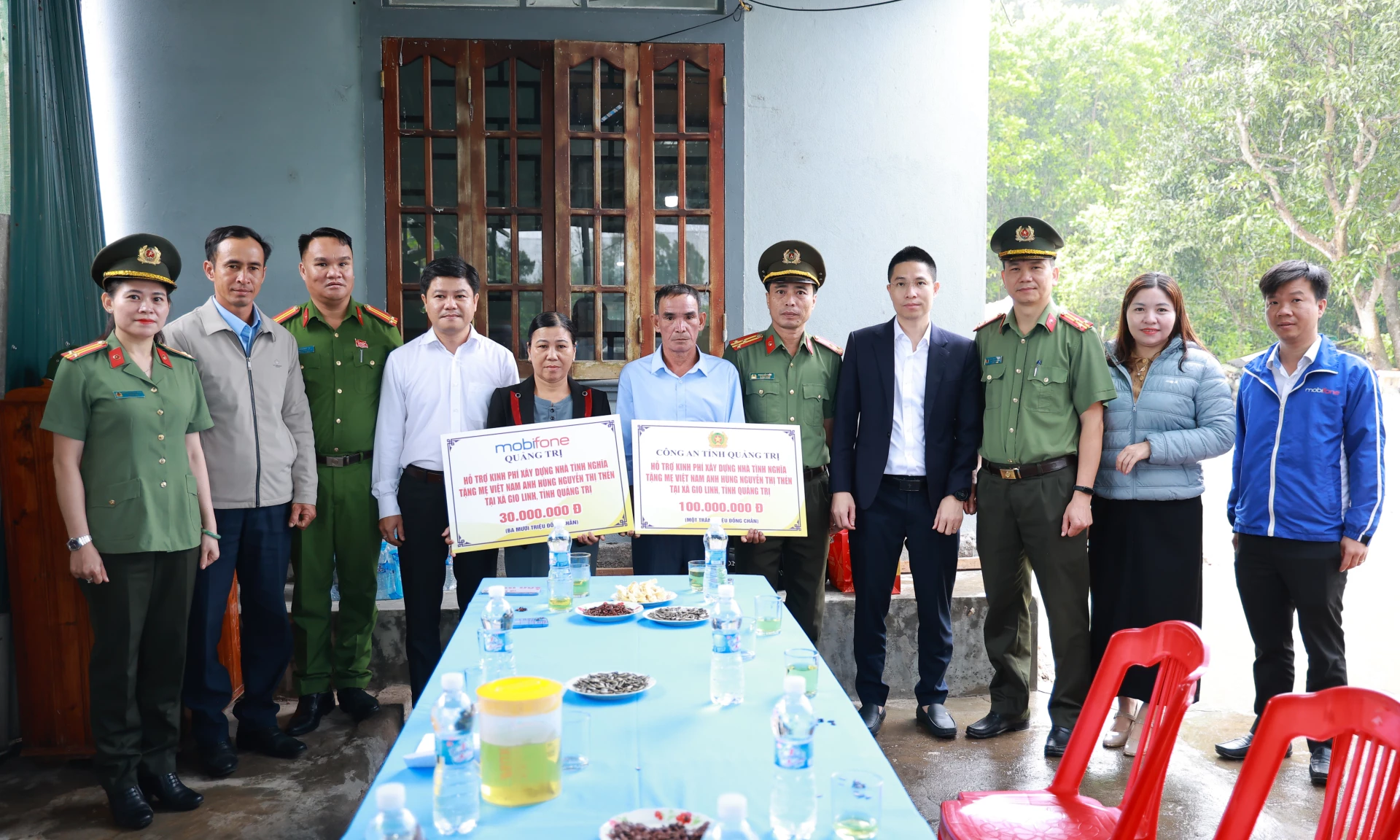 Đại diện lãnh đạo Công an tỉnh và Công ty Viễn thông MobiFone Quảng Trị trao biển tượng trưng hỗ trợ xây dựng nhà tình nghĩa cho gia đình mẹ Nguyễn Thị Thẻn - Ảnh: T.K