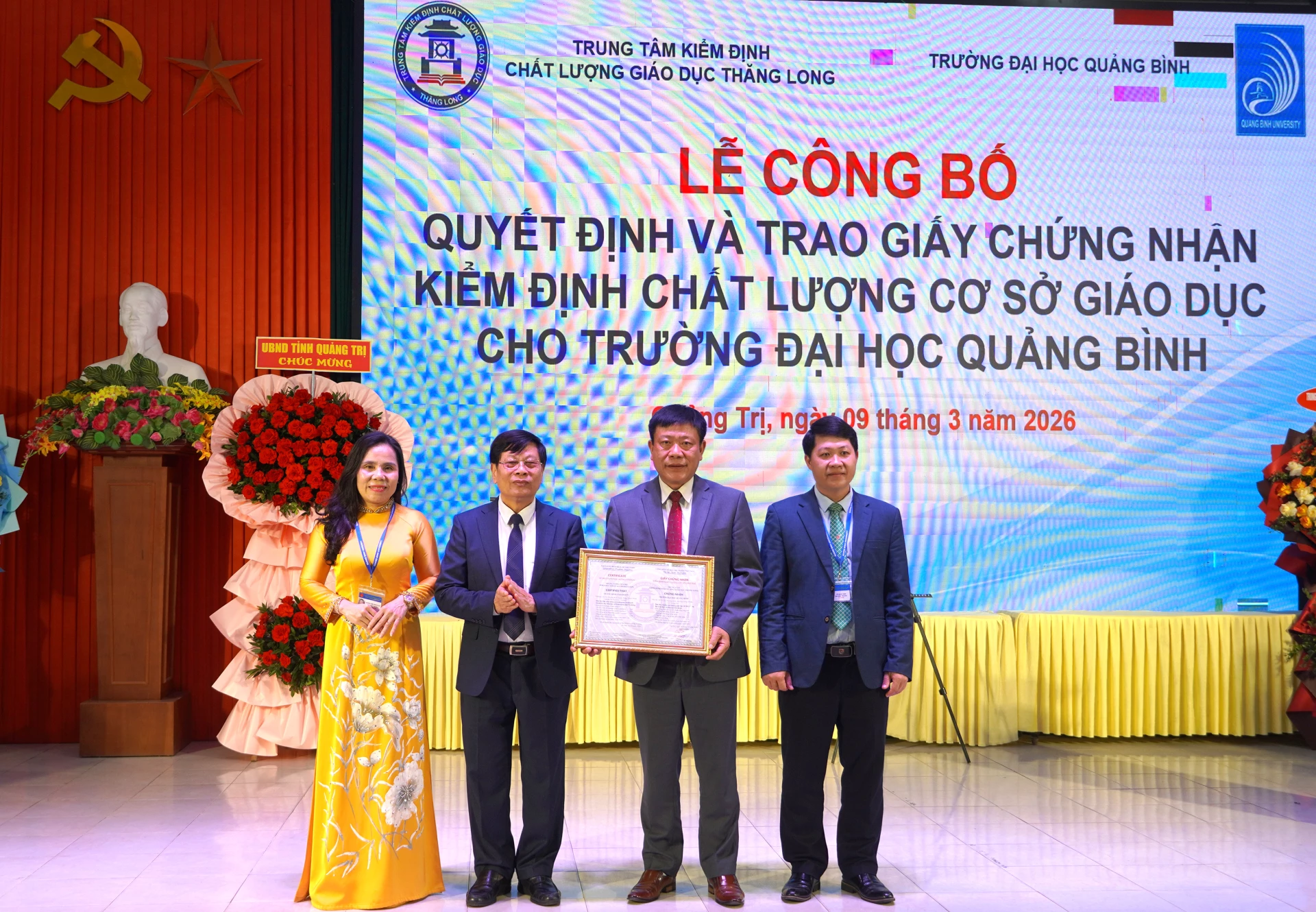 Giám đốc Trung tâm Kiểm định chất lượng giáo dục Thăng Long Nguyễn Văn Đường trao giấy chứng nhận kiểm định chất lượng cơ sở giáo dục và tặng hoa chúc mừng Trường đại học Quảng Bình - Ảnh: H.Tr.