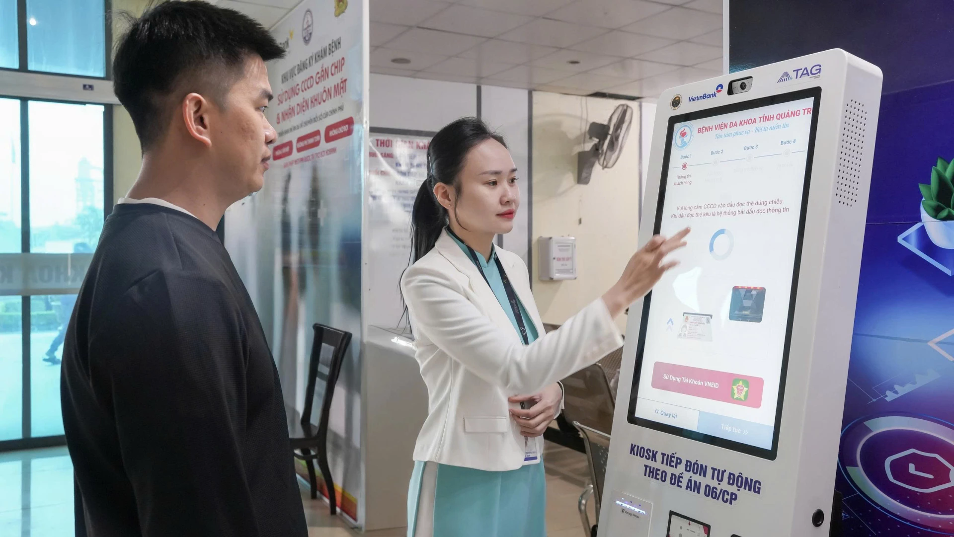 Nhân viên chăm sóc khách hàng hỗ trợ người dân đăng ký khám bệnh tại ki-ốt y tế thông minh - Ảnh: L.D