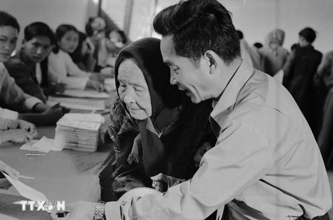 Ngày 25/4/1976, trên 23 triệu cử tri của nước Việt Nam thống nhất đã nô nức đi bầu cử. Đây thực sự là ngày hội lớn của toàn dân Việt Nam. Trong ảnh: Cụ Lê Thị Dưỡng (86 tuổi, thành phố Huế), già yếu vẫn nhờ người cõng đến hòm phiếu tham gia bầu cử đại biểu Quốc hội thống nhất (25/4/1976). (Ảnh: Sỹ Thái/TTXVN)