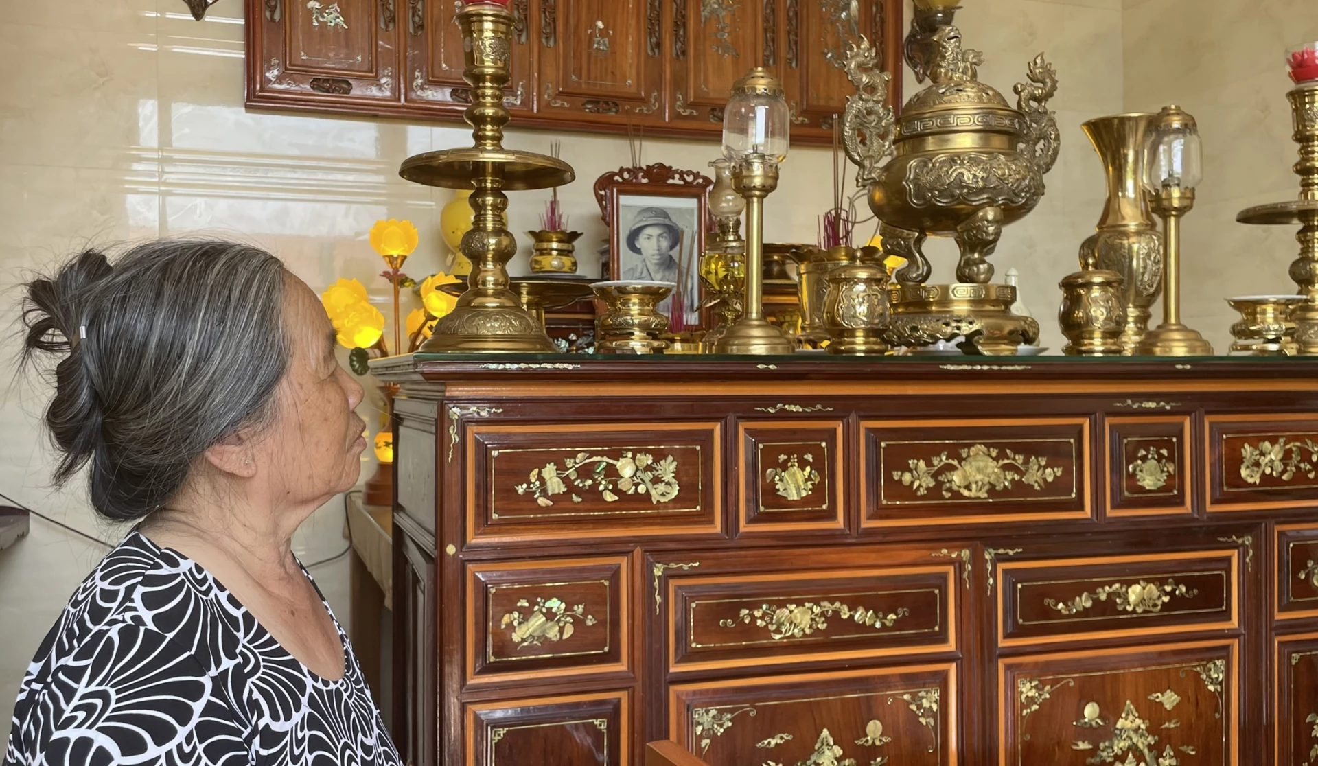 Bà Lại Thị Khuyên bên bàn thờ của chồng - Ảnh: L.T