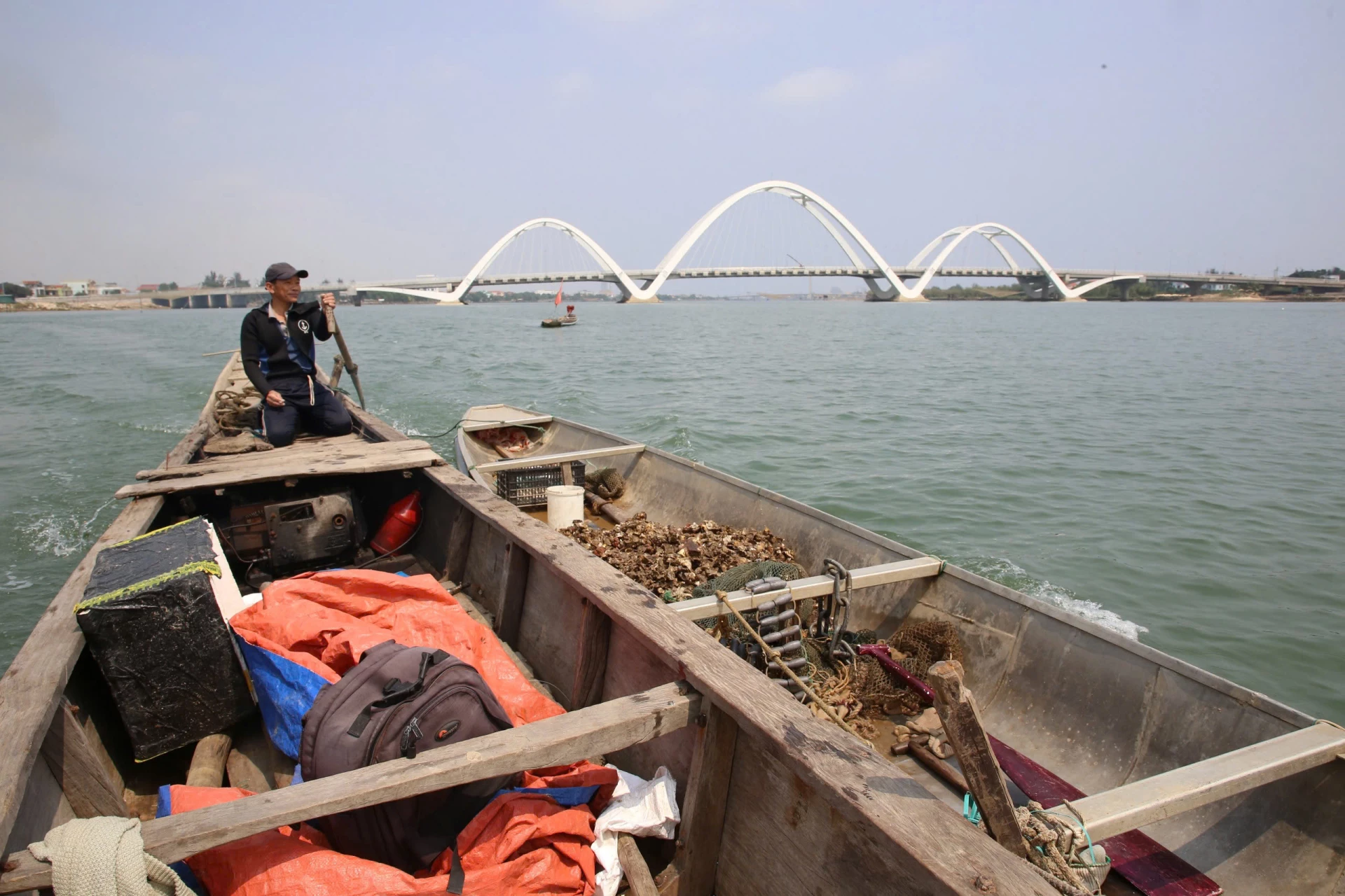 Ông Lê Đại Châu neo thuyền phía trên cầu Nhật Lệ 3, bắt đầu một ngày lặn hàu dưới đáy sông - Ảnh: P.P