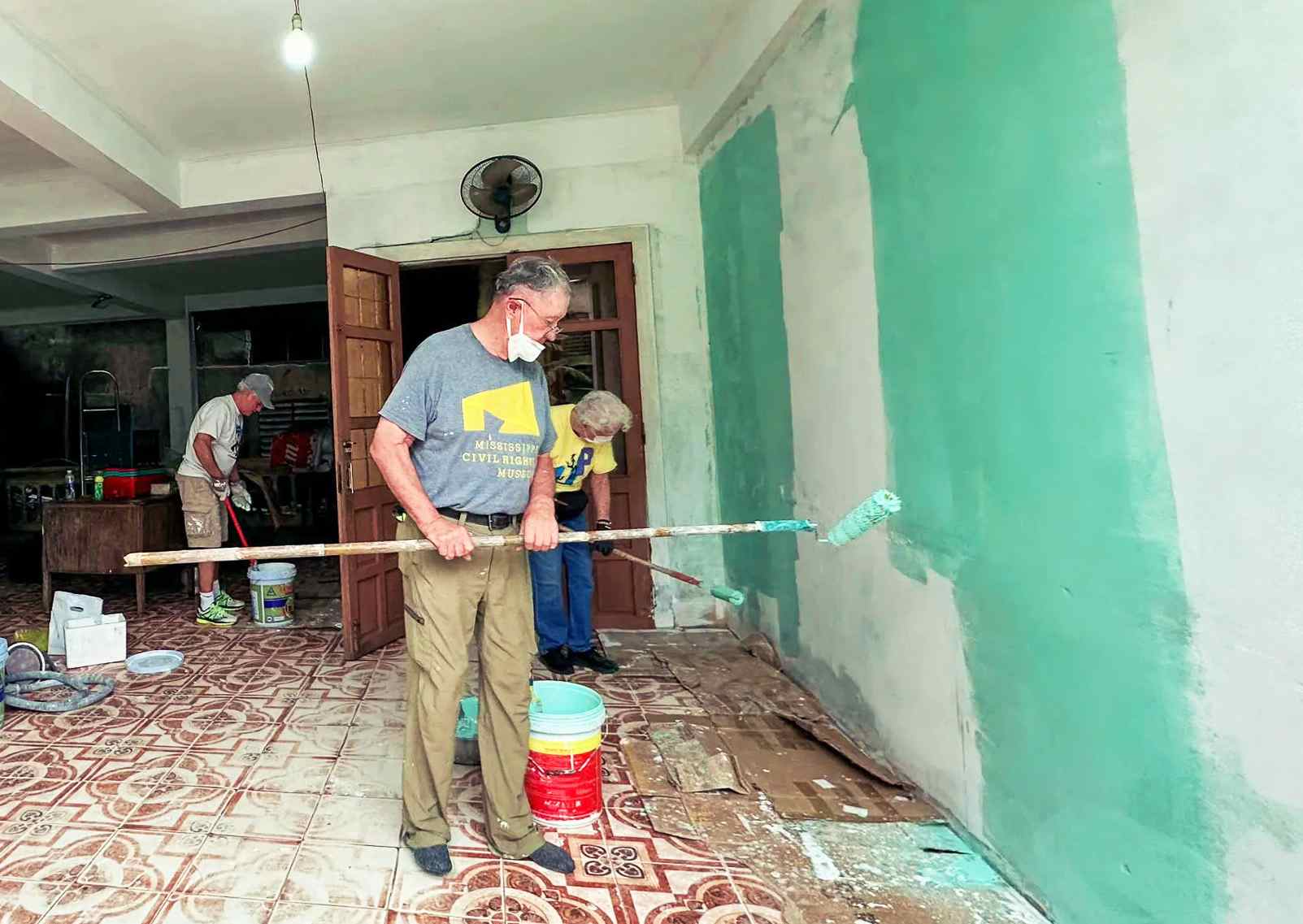 Thành viên nhóm UP giúp thay màu áo mới cho những bức tường tại xưởng sản xuất của Hội Người mù phường Đông Hà - Ảnh: Q.H