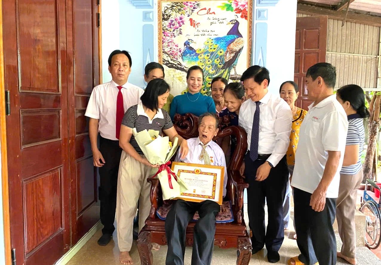 Đồng chí Lê Vĩnh Thế, Chánh Văn phòng Tỉnh ủy trao huy hiệu 80 năm tuổi Đảng cho đảng viên Trần Văn Yêm, ở xã Tân Mỹ - Ảnh: Minh Hà