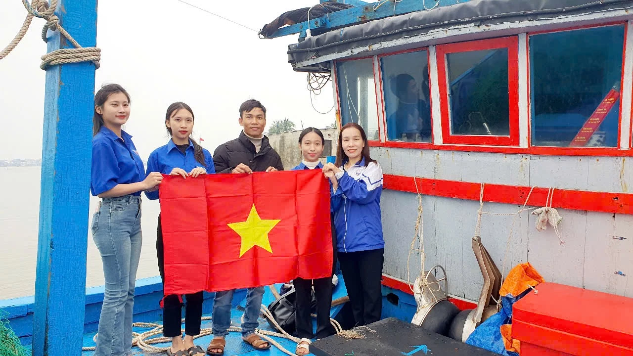 Các bạn học sinh trao cờ Tổ quốc cho ngư dân xã Cửa Việt - Ảnh: N.D