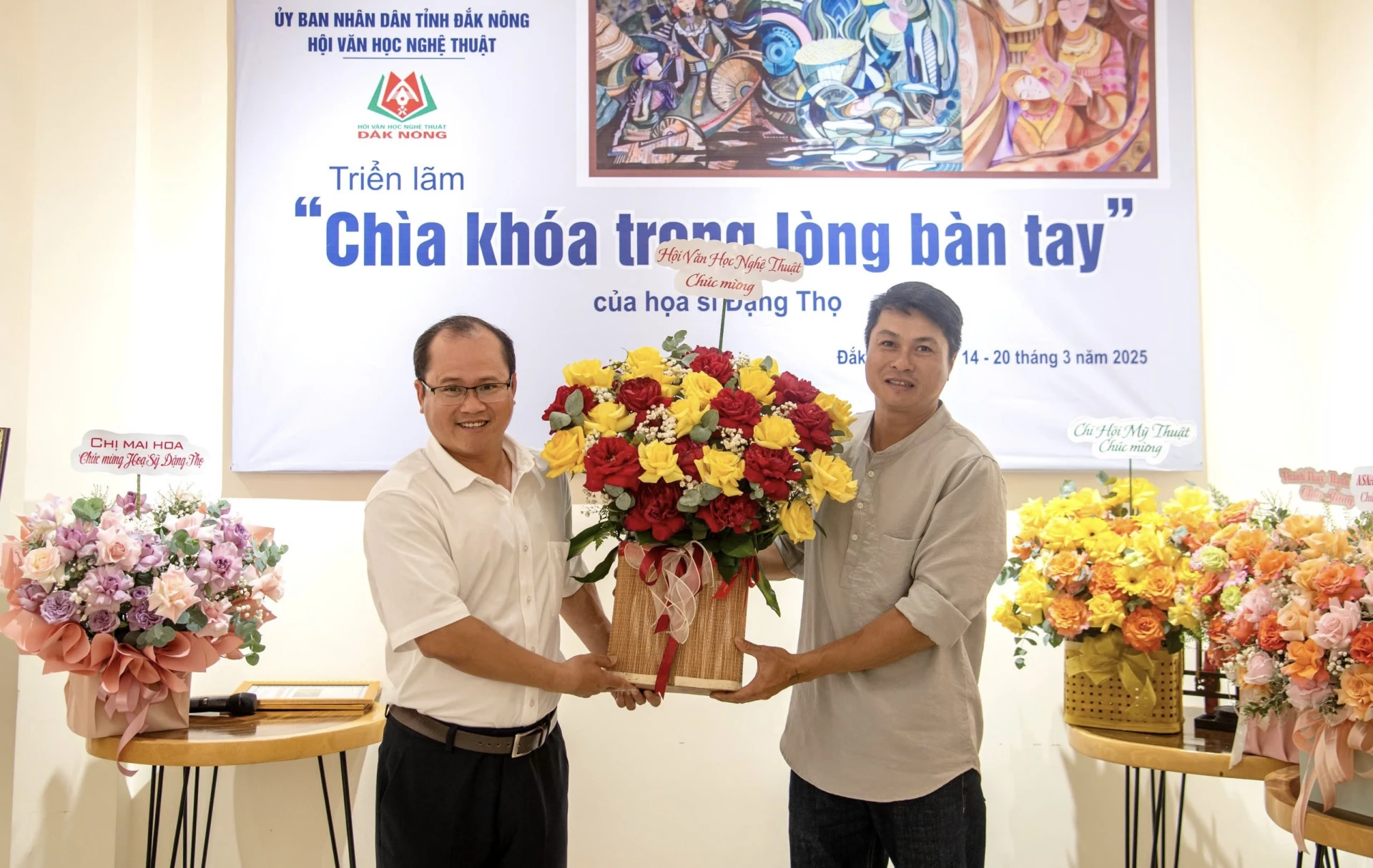 Nhà văn Đặng Bá Canh (bên trái), Chủ tịch Hội Văn học Nghệ thuật tỉnh Lâm Đồng tặng hoa chúc mừng họa sĩ Đặng Đại Thọ với triển lãm “Chìa khóa trong lòng bàn tay”  - Ảnh: NVCC