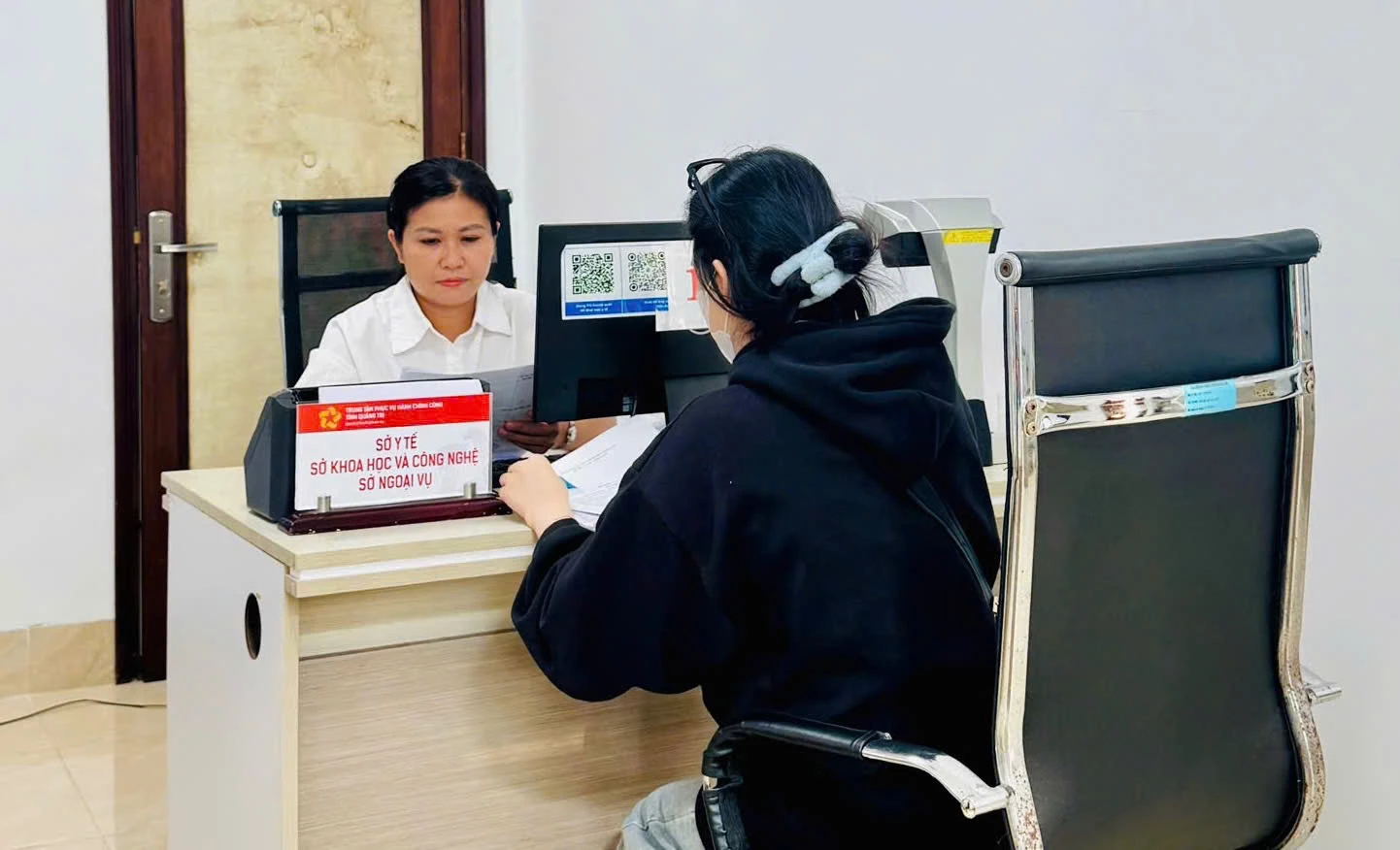 Cán bộ y tế hướng dẫn người dân làm thủ tục tại Trung tâm Phục vụ hành chính công tỉnh - Ảnh: H.N