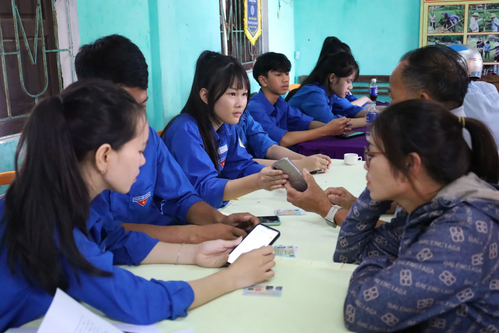 Đoàn viên thanh niên và thành viên tổ công nghệ số cộng đồng trực tiếp hướng dẫn tích hợp và sử dụng ứng dụng cho người dân - Ảnh: D.H