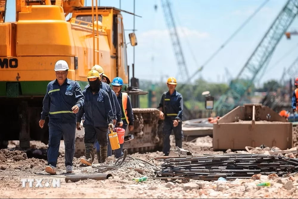 Nhóm công nhân tranh thủ di chuyển, nghỉ ngắn giữa ca làm việc ngoài trời tại công trường xây dựng. (Ảnh: Phạm Tuấn Anh/TTXVN)