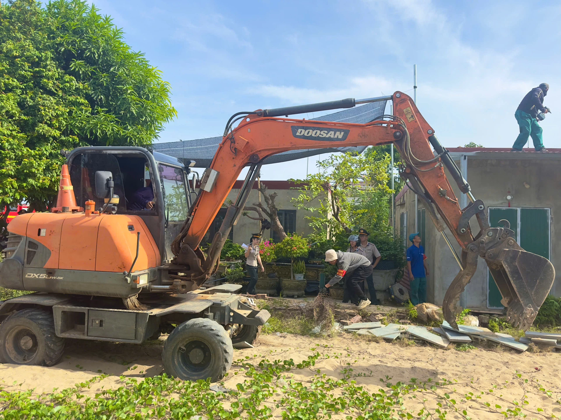 Lực lượng chức năng tiến hành tháo dỡ các công trình trên diện tích đất phải thi hành án - Ảnh: Thùy Trang