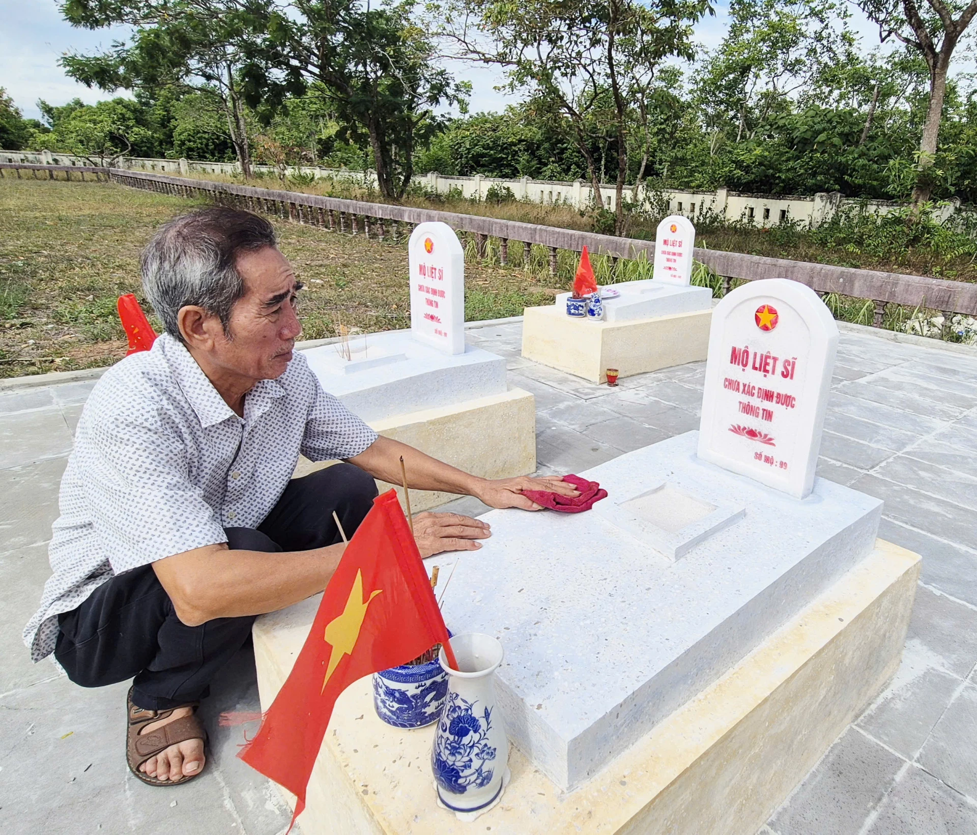 Ông Nguyễn Ngọc Tân cẩn mẫn lau chùi, chăm sóc chu đáo từng phần mộ liệt sĩ như người thân ruột thịt của mình-Ảnh: K.S