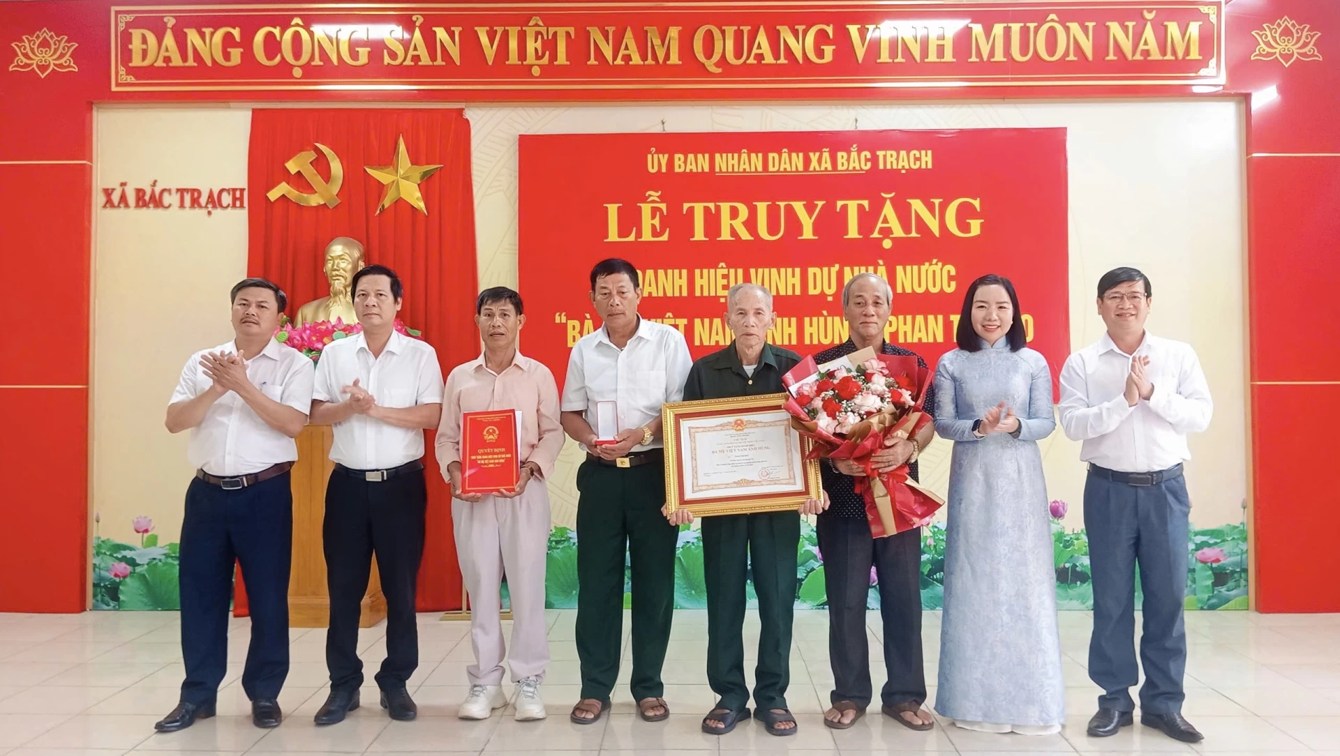 Đại diện lãnh đạo xã Bắc Trạch trao Quyết định truy tặng, Bằng, Huy hiệu và hoa chúc mừng thân nhân Mẹ Phan Thị Bẽo - Ảnh: K.H