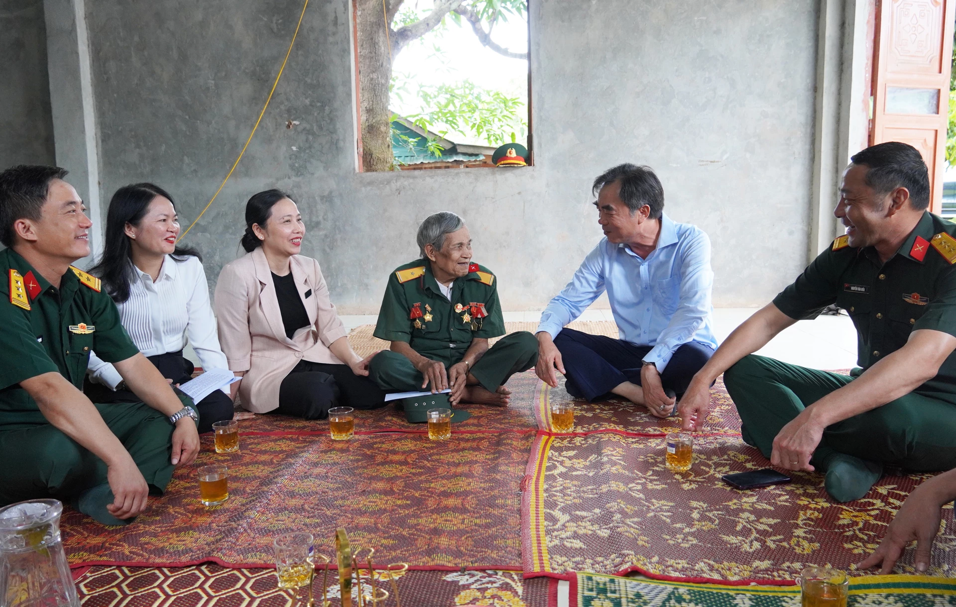 Đồng chí Nguyễn Lương Bình, Trưởng ban Tổ chức Tỉnh ủy và các thành viên đoàn công tác trò chuyện, động viên bệnh binh Hồ Văn Đăm, ở thôn Ra Po, xã A Dơi - Ảnh: X.P