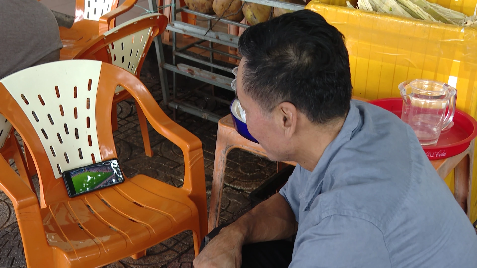 Ông Dương Quang Phước tranh thủ theo dõi các trận cầu World Cup trên điện thoại - Ảnh: LT