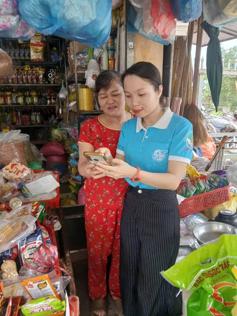 Cán bộ phụ nữ hướng dẫn người dân sử dụng thanh toán không dùng tiền mặt - Ảnh: N.P