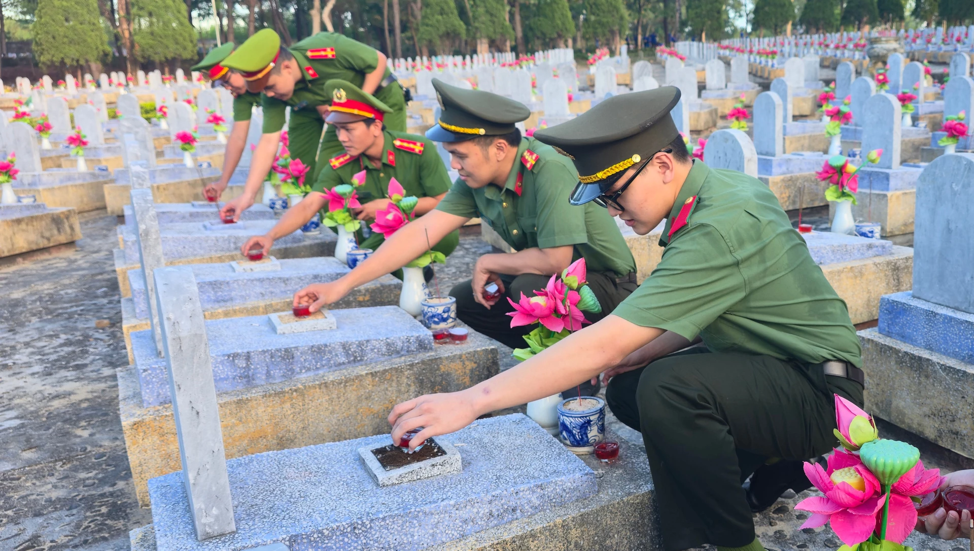 Sinh viên Hà Minh Huy (người ngoài cùng bên phải) chăm sóc các phần mộ tại Nghĩa trang liệt sĩ quốc gia Đường 9, chuẩn bị cho cầu truyền hình “Sao sáng dẫn đường” - Ảnh: N.M