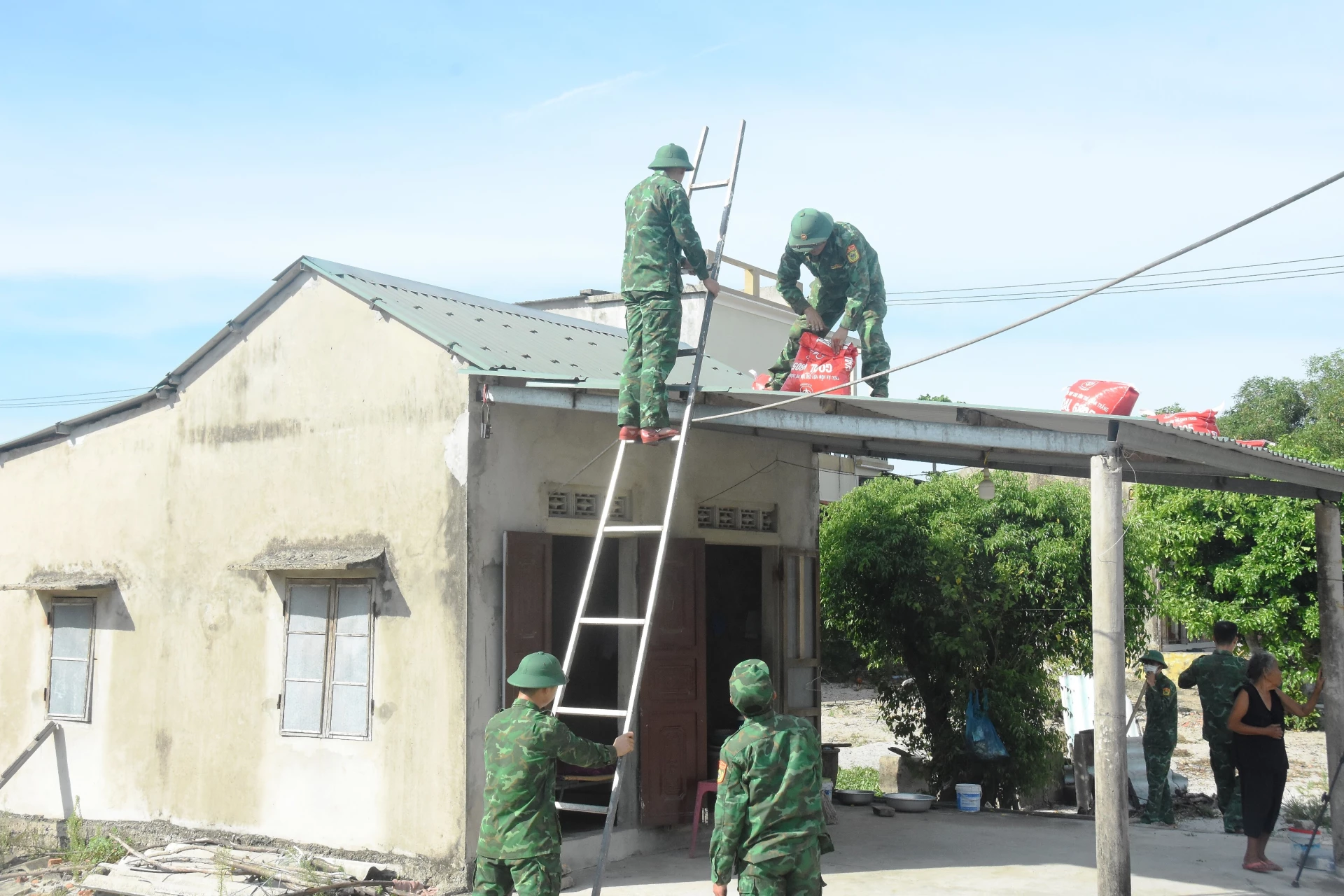 Cán bộ, chiến sĩ Đồn Biên phòng Triệu Vân giúp người dân chằng chống nhà cửa chống bão số 5 - Ảnh: ĐV