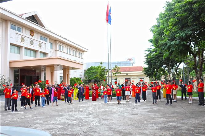 Cán bộ, nhân viên Đại sứ quán Việt Nam tại Lào giơ cao lá cờ đỏ sao vàng hướng về Tổ quốc. Ảnh: Xuân Tú/PV TTXVN tại Lào