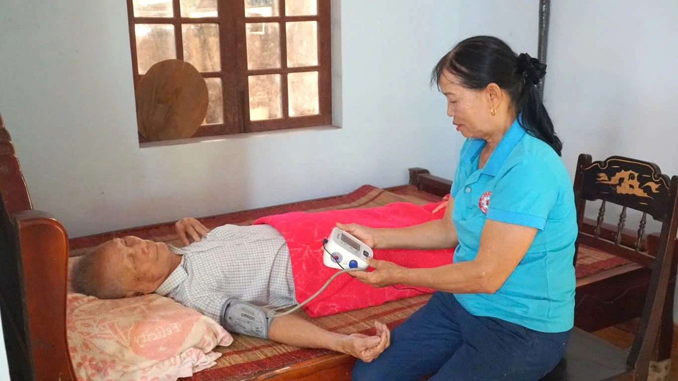 Chị Chiến kiểm tra huyết áp cho người già trong thôn - Ảnh: T.T 