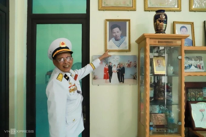 Trung tá Lê Xuân Sênh bên cạnh bức ảnh kỷ niệm chụp vội ở Đông Triều, Quảng Ninh trước năm 1969, khi chuẩn bị nhận nhiệm vụ tại biển Cửa Việt, Quảng Trị. Ảnh: Quỳnh Nguyễn