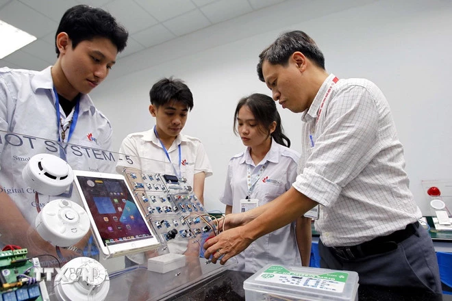Giảng viên Khoa công nghệ điện tử Trường Đại học Công nghiệp Thành phố Hồ Chí Minh hướng dẫn sinh viên học tập, nghiên cứu tại Phòng thí nghiệm IoT and AI. (Ảnh: Thanh Vũ/TTXVN)