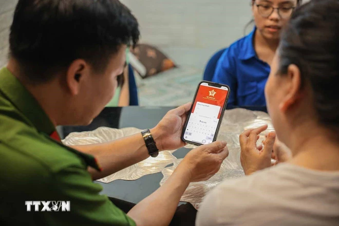 Tổ chuyển đổi số cộng đồng hướng dẫn người dân sử dụng ứng dụng định danh công dân trên môi trường kỹ thuật số (VNeID) có giá trị sử dụng thay thế các giấy tờ truyền thống. (Ảnh: Hoàng Hiếu/TTXVN)