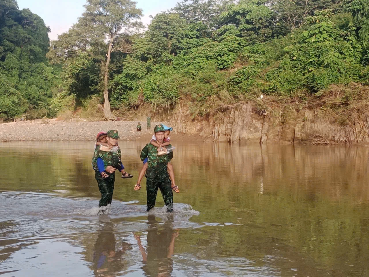 Để kịp giờ khai giảng, cán bộ chiến sĩ Đồn Biên phòng Hướng Lập cõng học sinh vượt suối đi đường tắt - Ảnh: L.T