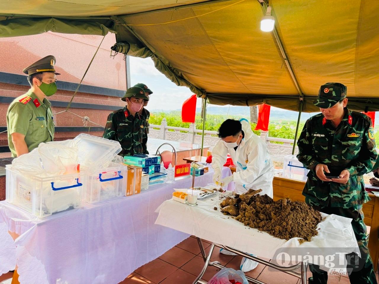 Lực lượng chức năng phường Đồng Sơn tiến hành lấy mẫu ADN từ hài cốt liệt sĩ tại Nghĩa trang liệt sĩ Đồng Sơn - Ảnh: B.N