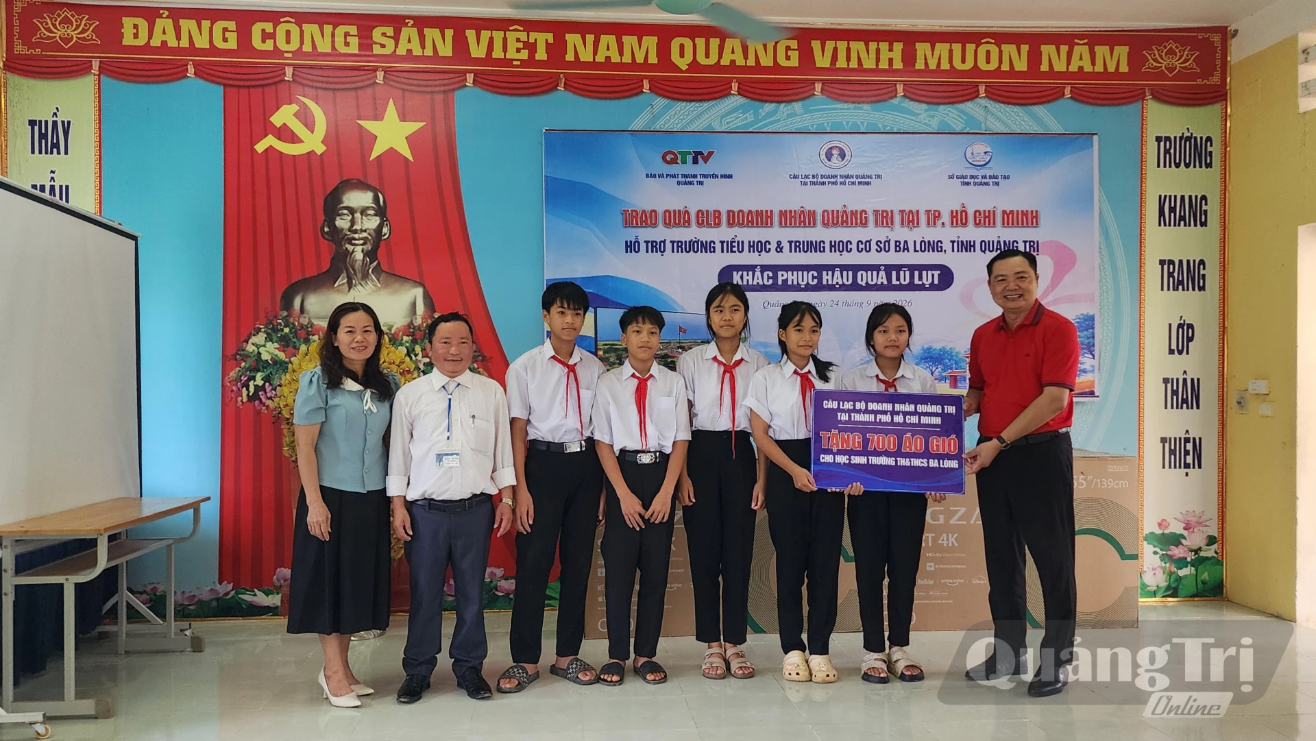 Đại diện Câu lạc bộ Doanh nhân Quảng Trị tại TP. Hồ Chí Minh trao bảng tượng trưng 700 áo gió tặng các em học sinh - Ảnh: Tạ Hưng
