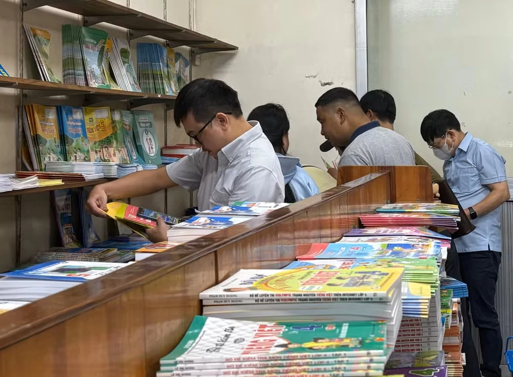 Phụ huynh tìm mua sách giáo khoa sau lễ khai giảng. (Ảnh: Phạm Mai/Vietnam+)