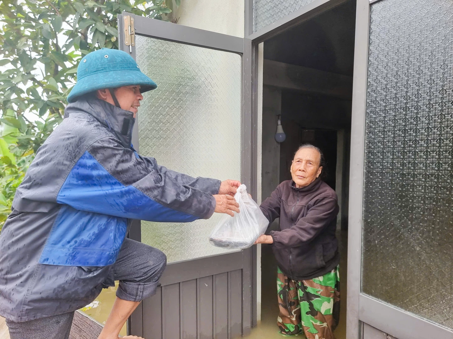 Người dân thôn An Thơ, xã Nam Hải Lăng được tiếp tế cơm tận nơi khi đang mắc kẹt do mưa lũ - Ảnh: L.T