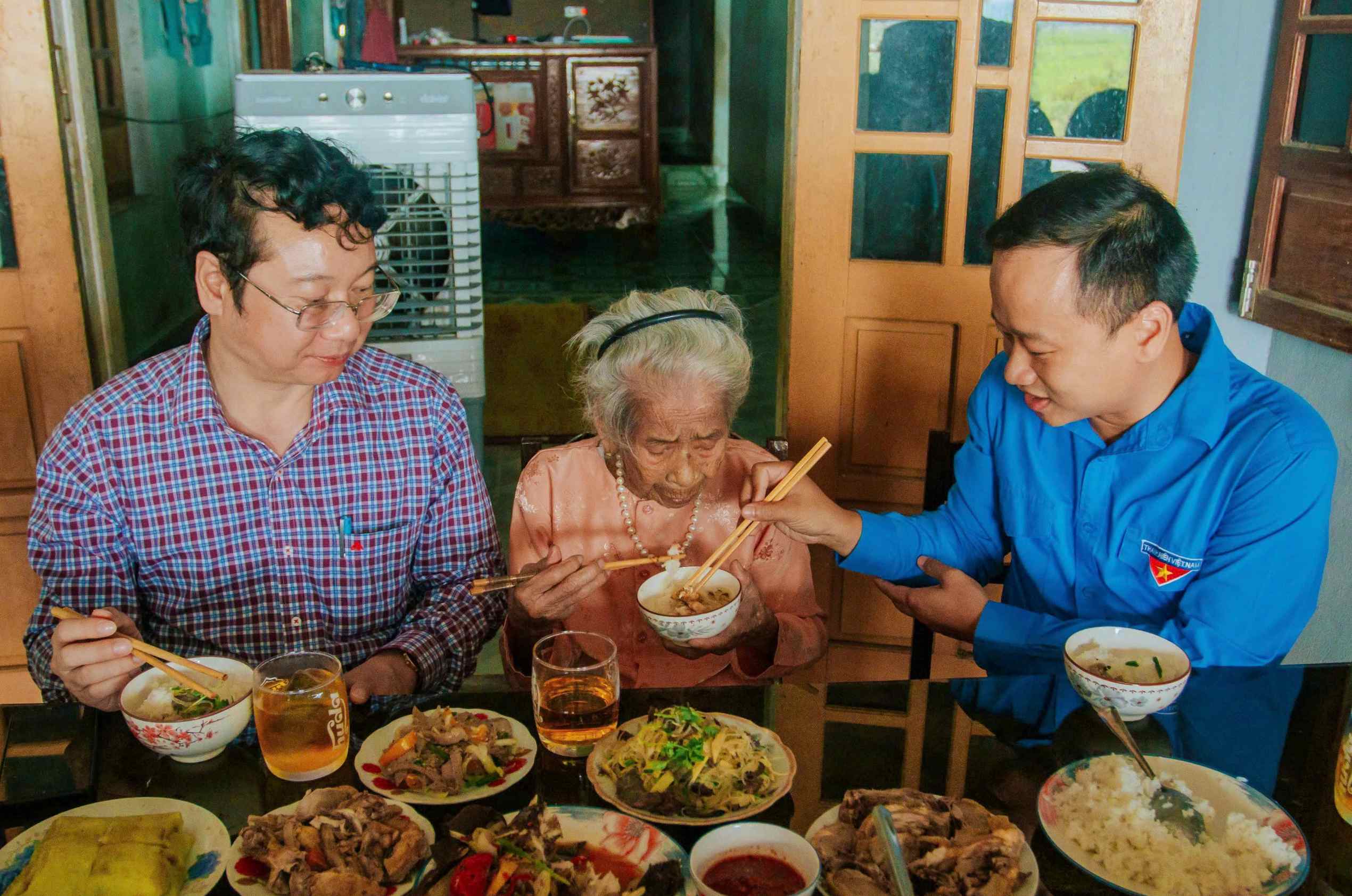 Anh Nguyễn Quốc Toản (bên phải) dùng bữa cơm với Bà mẹ Việt Nam anh hùng trong một chương trình tri ân - Ảnh: Q.H