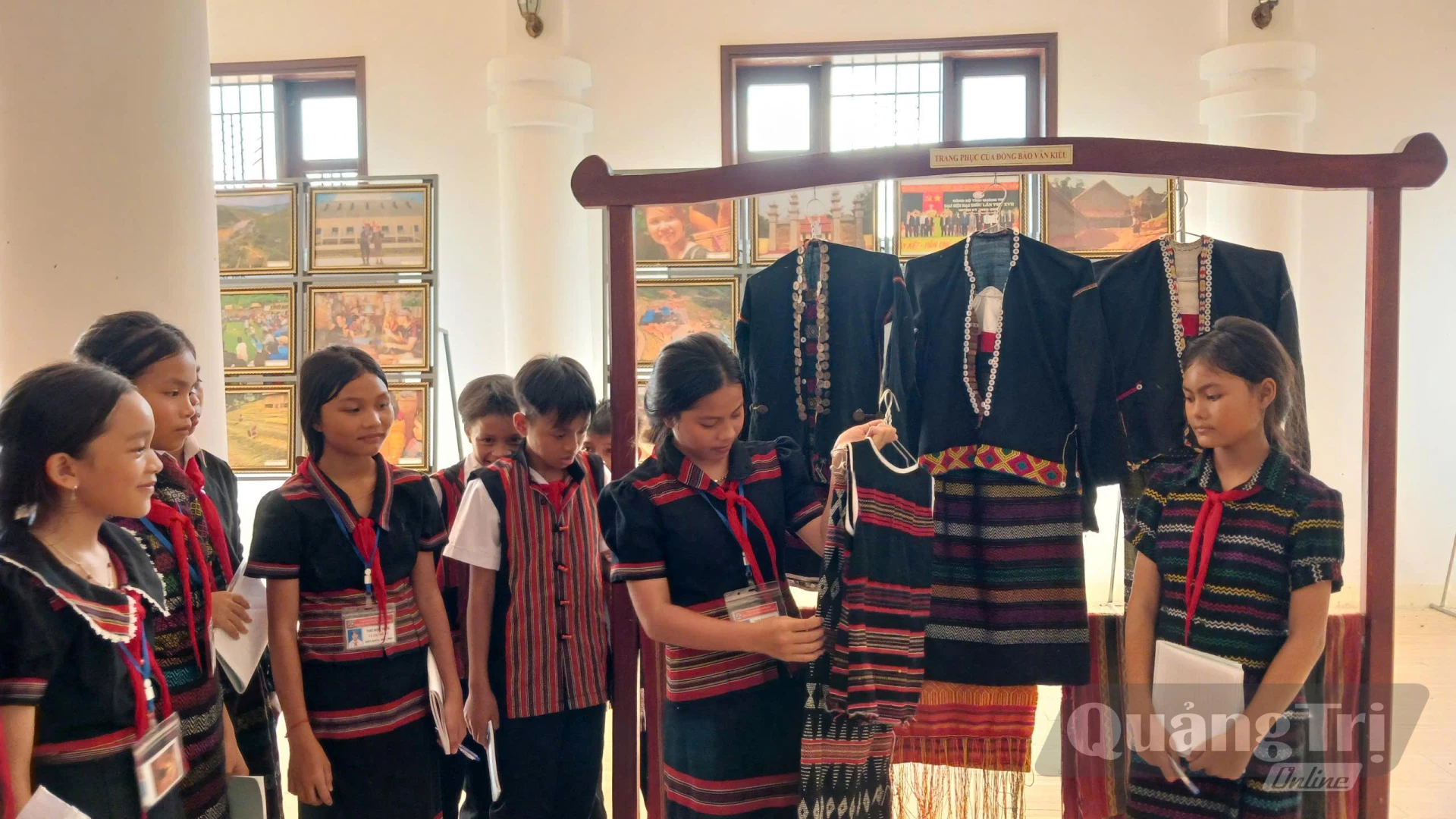 Em Hồ Thị Thảo Nhi, học sinh lớp 7B, Trường phổ thông Dân tộc nội trú Đakrông (người cầm áo) cùng các bạn tìm hiểu trang phục truyền thống của đồng bào mình - Ảnh: N.B