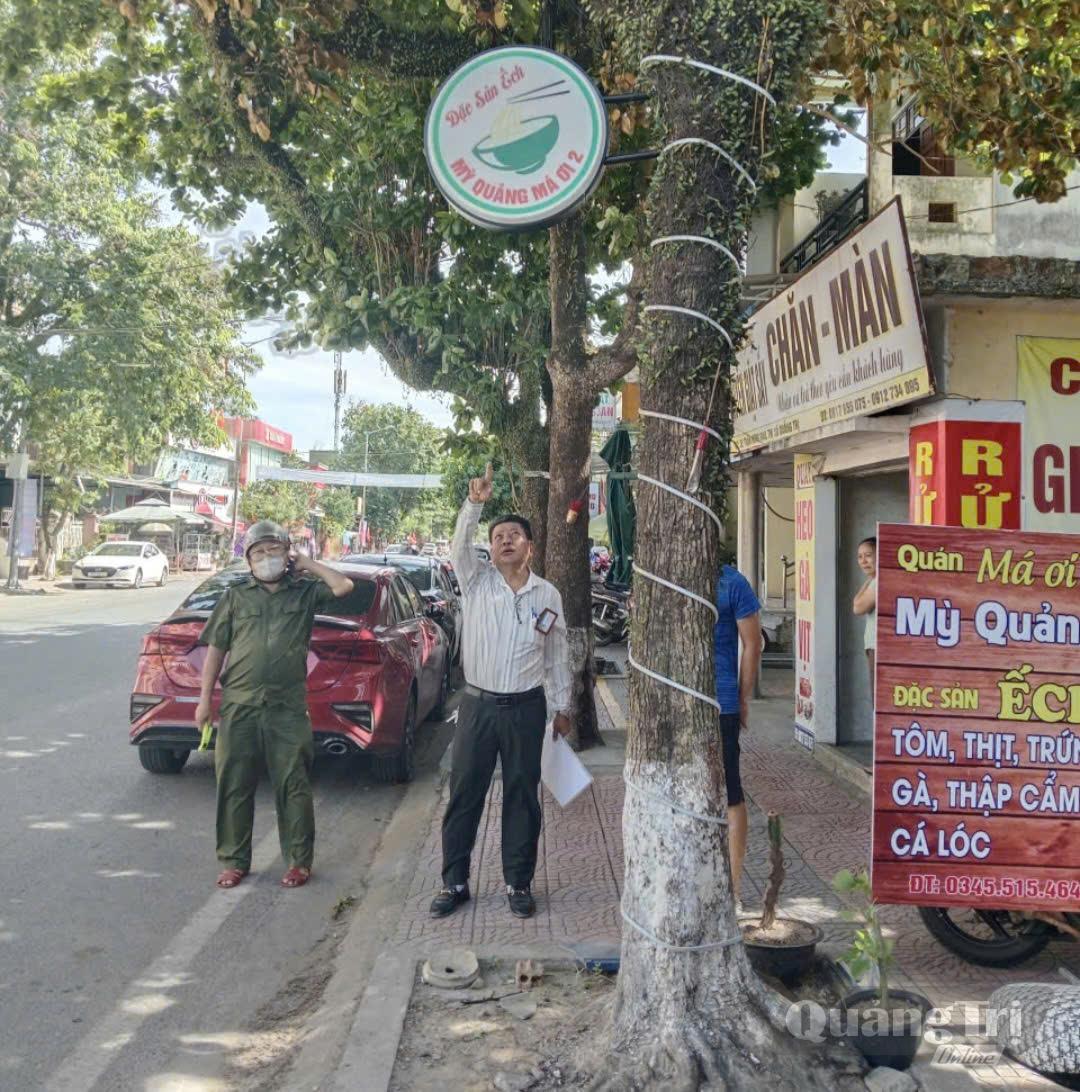 Anh Lý Quang Hào cùng lực lượng chức năng kiểm tra, hướng dẫn người dân treo biển hiệu đúng quy định, bảo đảm trật tự hành lang an toàn giao thông-Ảnh: K.S