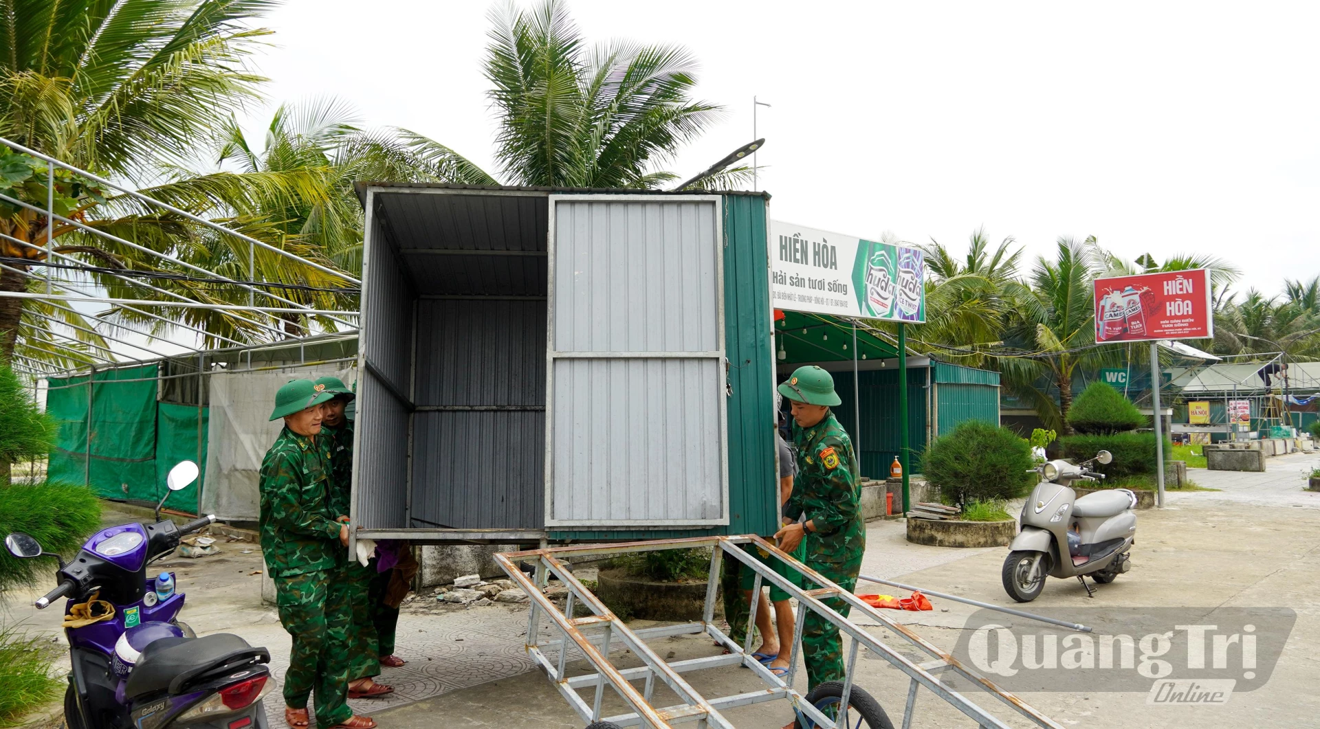 Các lực lượng chức năng hỗ trợ các hộ dân tháo dỡ công trình quán - Ảnh: H.Tr