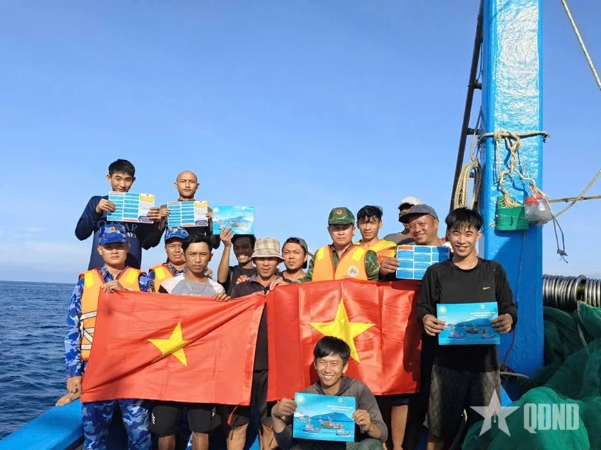 Hải đoàn Biên phòng 48 (Bộ tư lệnh Bộ đội Biên phòng) phối hợp với Vùng Cảnh sát biển 2 phát tờ rơi tuyên truyền pháp luật và tặng ngư dân cờ Tổ quốc. Ảnh: TẤN SANG