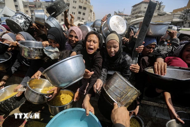 Người tị nạn nhận thức ăn cứu trợ tại thành phố Gaza, ngày 10/8. (Ảnh: THX/TTXVN)