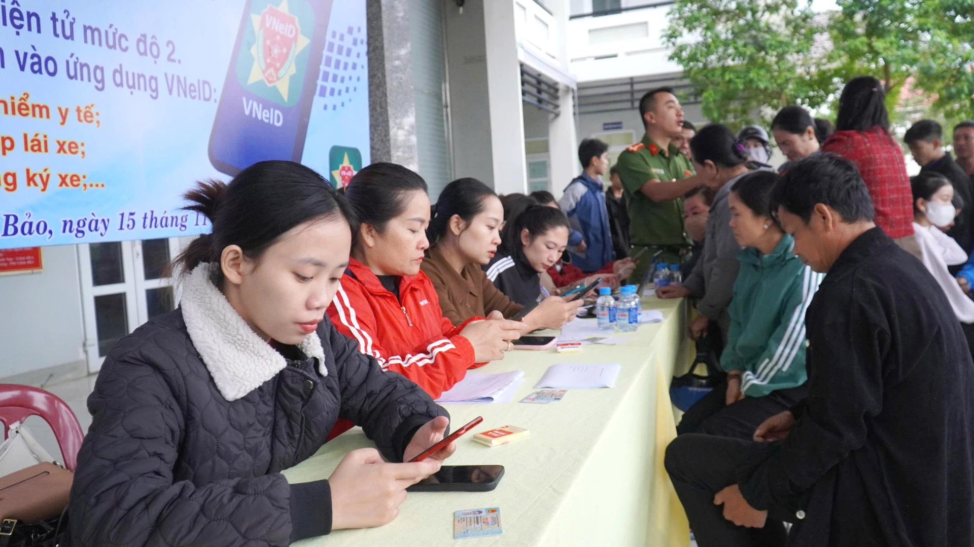 Cán bộ UBND xã Lao Bảo được huy động nhằm giúp người dân thực hiện tích hợp các loại giấy tờ lên tài khoản VNeID mức 2 - Ảnh: Đ.V