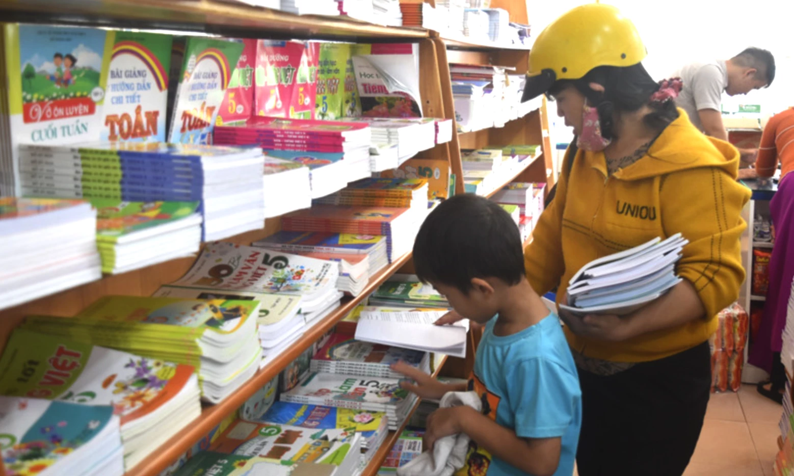 Phụ huynh, học sinh lựa chọn sách giáo khoa. (Ảnh: TTXVN)