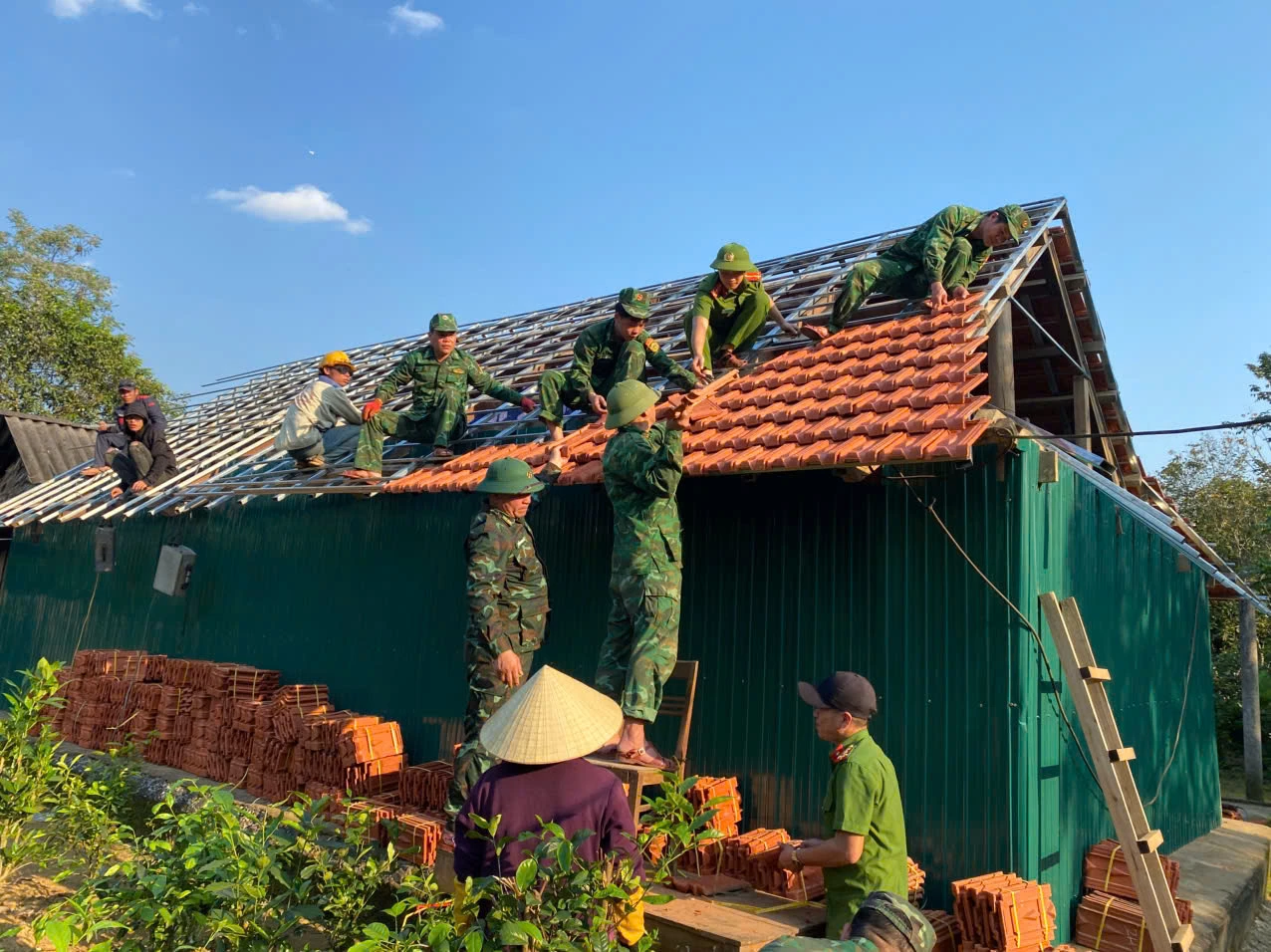 Cán bộ, chiến sĩ Đồn Biên phòng Cà Xèng phối hợp với các lực lượng và chính quyền địa phương xây dựng nhà ở cho người dân thôn Đặng Hóa, xã Kim Điền - Ảnh: L.T