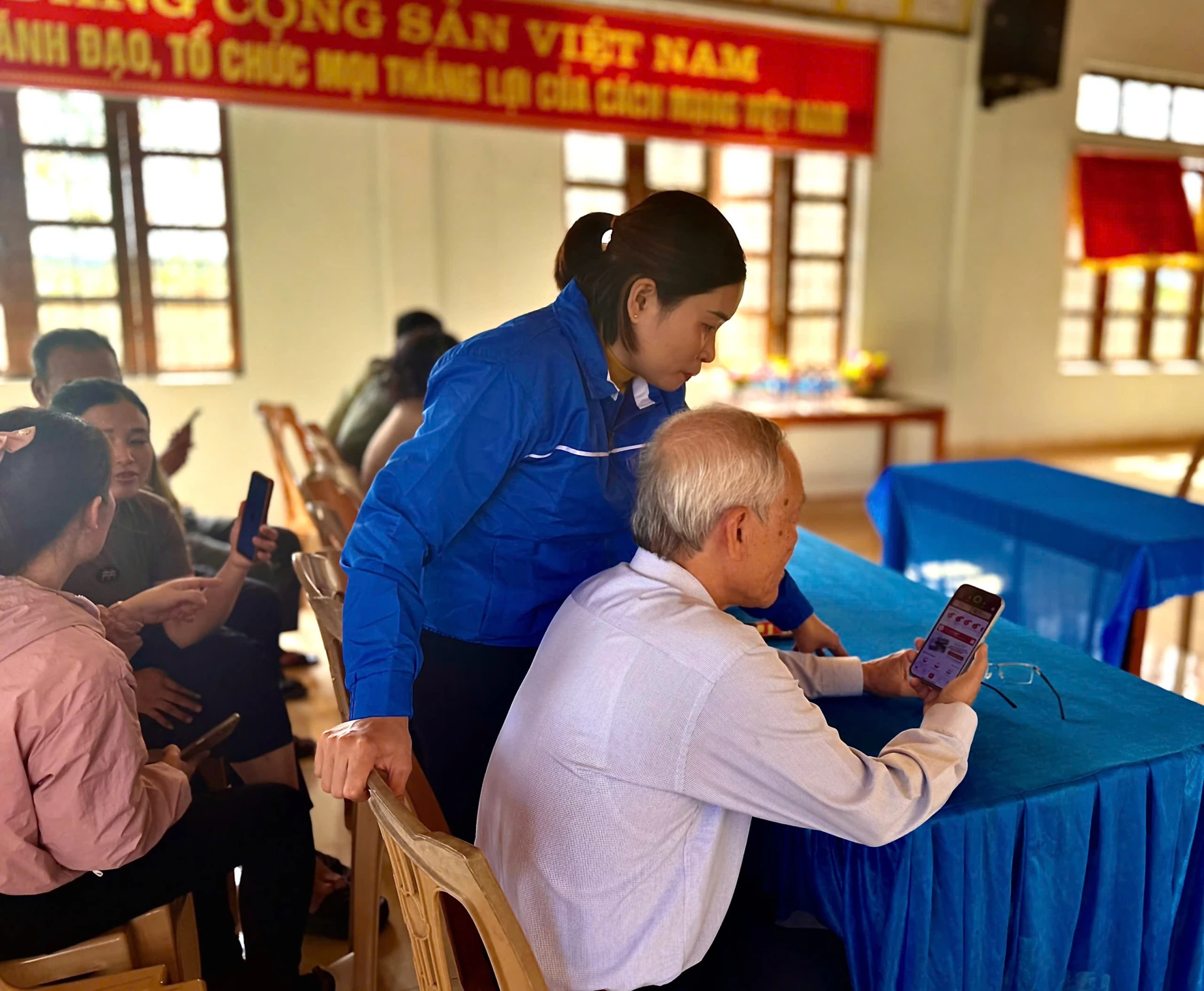 Thành viên Tổ Công nghệ số cộng đồng và Đề án 06 thôn Hà Tiến hướng dẫn người dân tích hợp thẻ bảo hiểm y tế, sổ sức khỏe điện tử trên ứng dụng VNeID - Ảnh: H.N