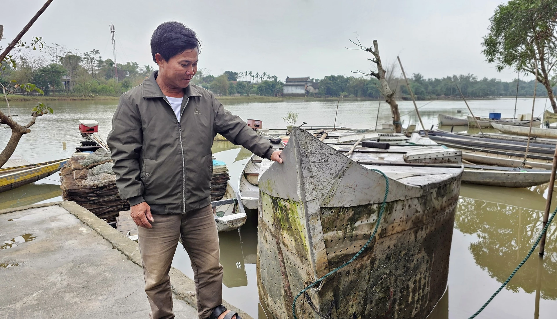 Anh Phạm Văn Thiện bên lồng nuôi cá chình hình mũi thuyền của mình - Ảnh: L.A